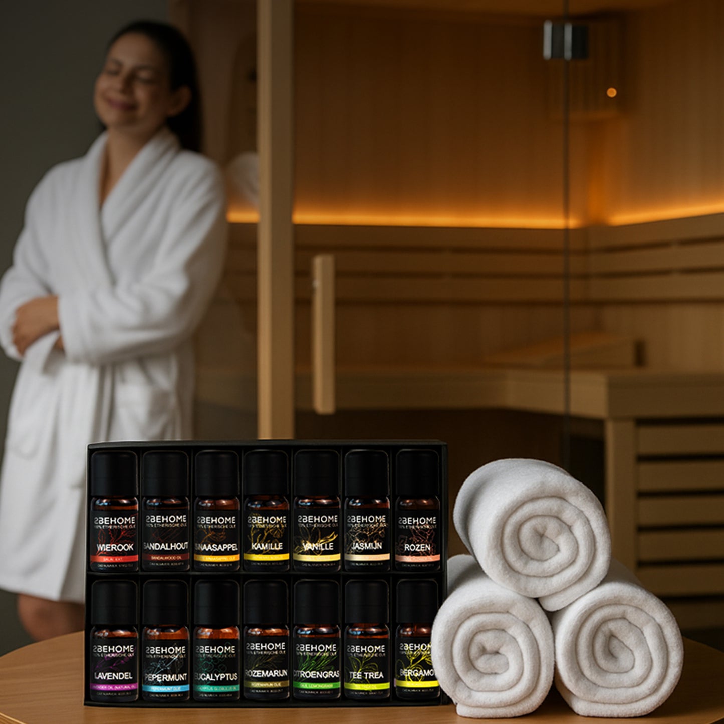 Een vrouw geniet van een sauna in haar badjas. In de welness zie je ook de essentiele olieset op tafel staan, met wat handdoekjes ernaast.